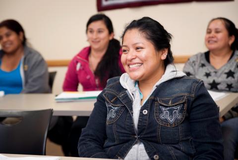 101413clues049.jpg Girl sitting in classroom smiling with other women