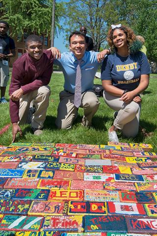 denby-high-school-05-620.jpg Three people kneeling by a pathway of painted bricks