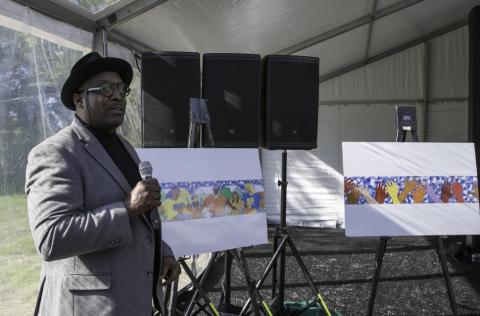 Artist Hubert Massey and renderings of murals for park Artist Hubert Massey, holds microphone, by renderings of his park murals