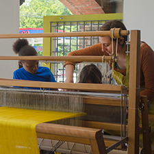 Young woman with two children at a loom