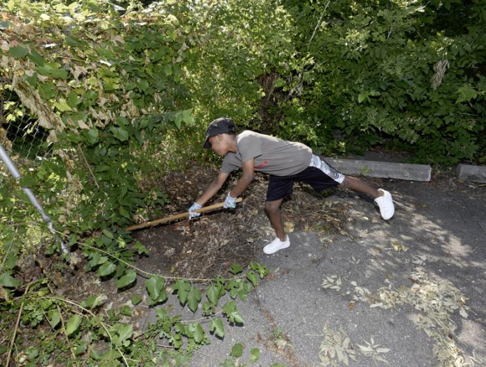 Travis Bussey, 11, helps clean up the fence line in the parking lot across the street from the Bethel A & E Church on Detroit's East side during Saturday's 12th Annual Arise Detroit Neighborhoods Day. 