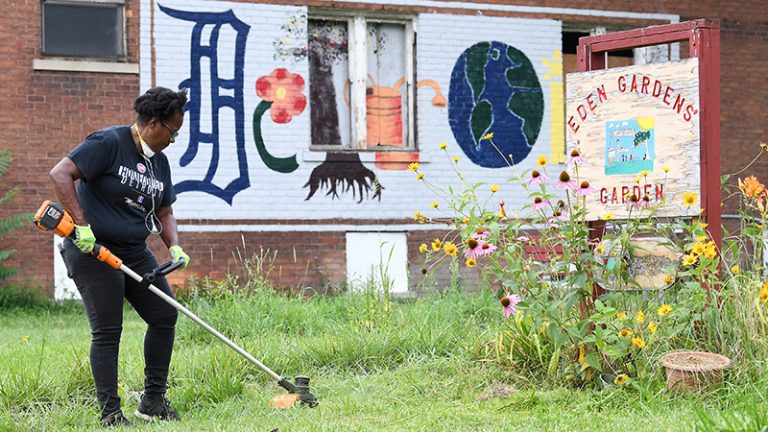 A woman in a field is sprucing up the grounds at Eden Gardens on Detroit's east side,