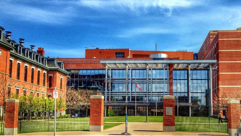 A large hospital building of red brick and a glass entrance.