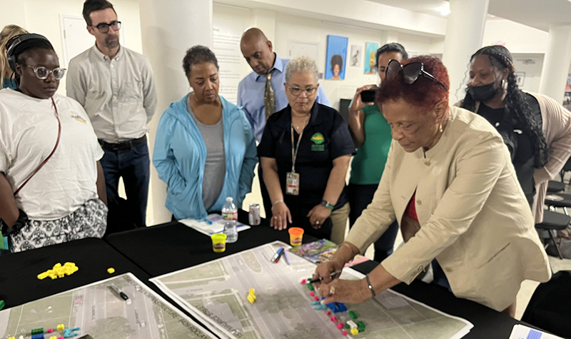 members of a community gathered around a a table observing a environmental plan. 