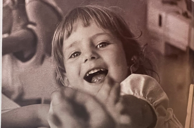 A young child is smiling and reaching out in a 1968 black-and-white photo from the Clarke School for the Deaf