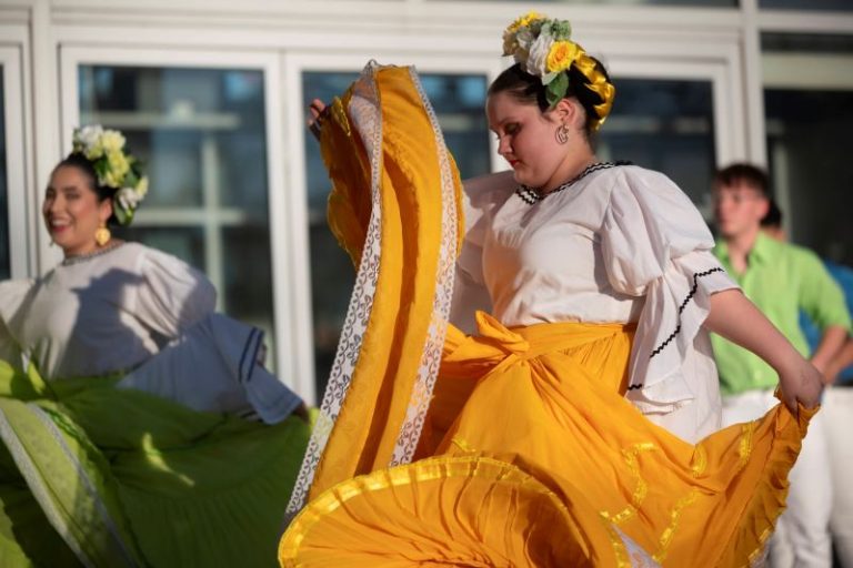 A performance by the Milagro Compañía de Ballet Folklórico with women in colorful dresses and flowered headdresses.