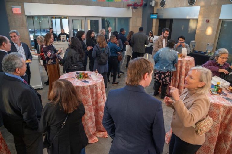 A large group of people at the MexicanTown CDC Mercado in southwest Detroit at the Eminent Artist monograph celebration with food, drinks and colorful decorations.