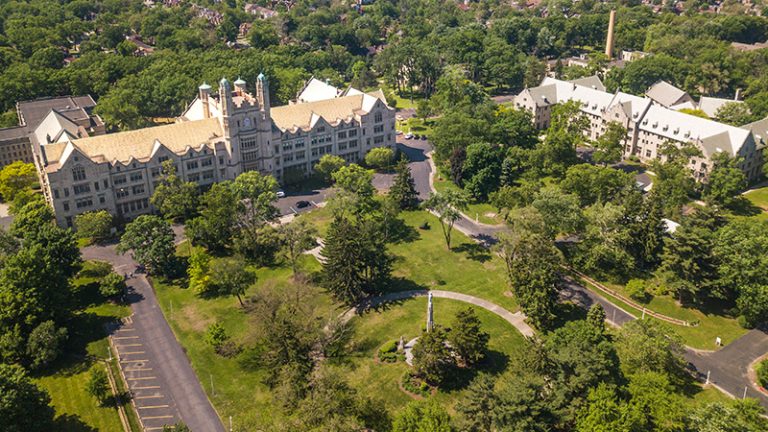 An aerial shot of the Marygrove campus in northwest Detroit with two Tudor Gothic style buildings amid trees and green space.
