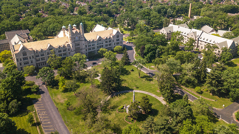 An aerial shot of the Marygrove campus in northwest Detroit with two Tudor Gothic style buildings amid trees and green space.