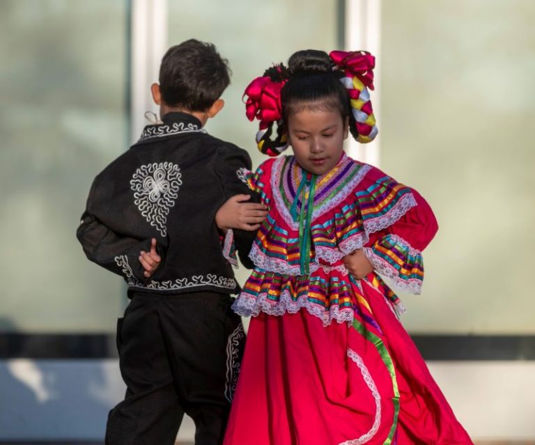 A performance by the Milagro Compañía de Ballet Folklórico with two children dancing arm in arm.