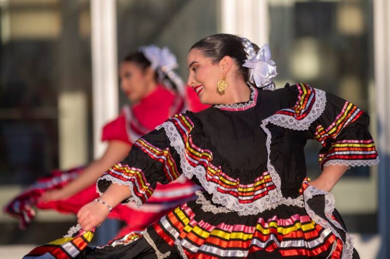 A performance by the Milagro Compañía de Ballet Folklórico with women in colorful dresses and flowered headdresses.