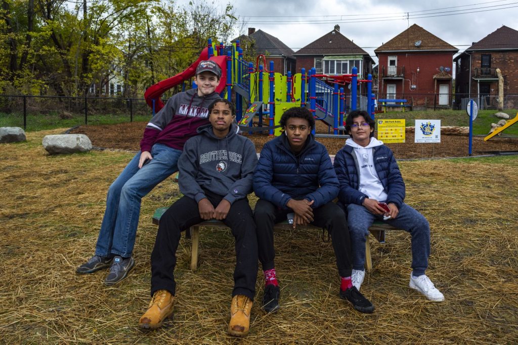 Four youth, seemingly young teens, sit on a park playscape.