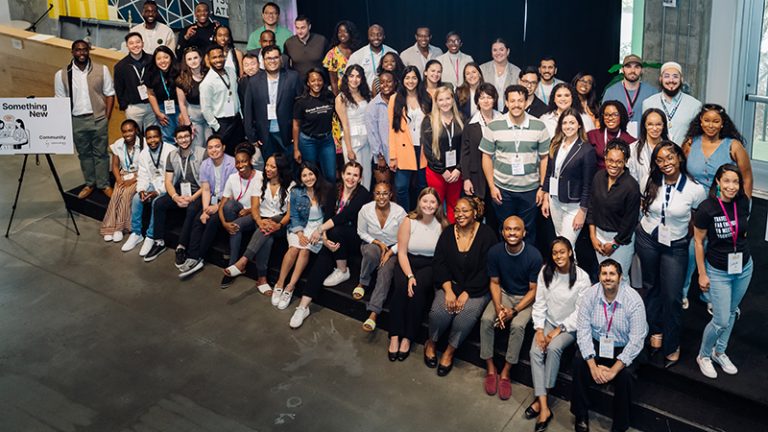 A large group of people some sitting and some standing on a stage pose for a photo.