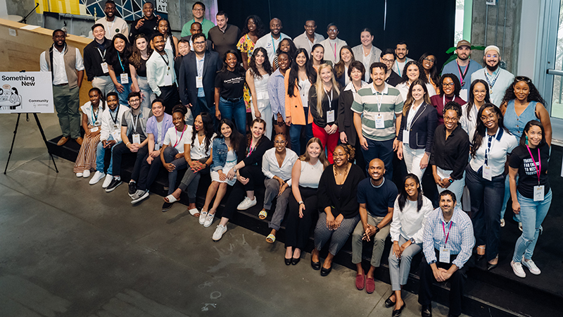 A large group of people some sitting and some standing on a stage pose for a photo.