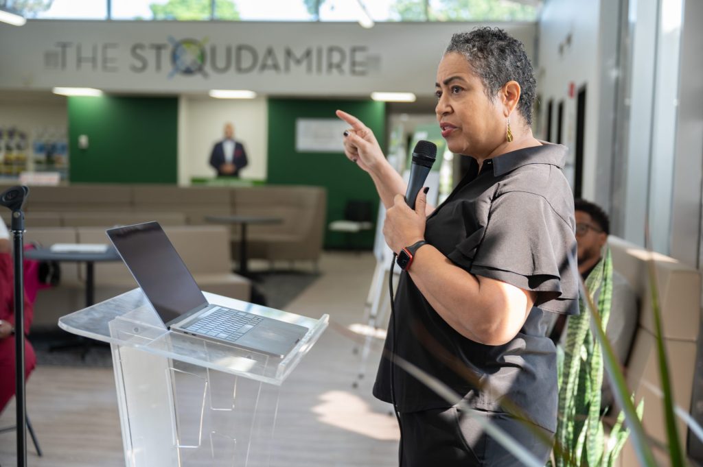 ECN's Donna Givens Davidson is standing at a podium and speaking with at microphone at an event the Resilience Network.