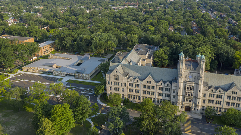 An aerial view of the Marygrove Conservancy Campus with a focus on a large historic Gothic Tudor structure and a modern , low-level terra-cotta early childhood edcuation center.