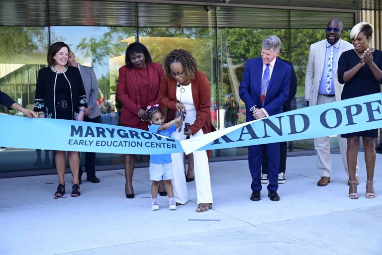 Small child and school principal cut the ribbon for the grand opening of the Marygrove Early Education Center
