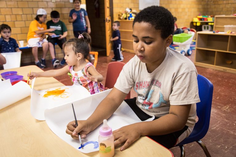 Child paints on table top in childcare center
