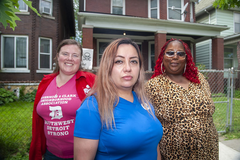 Three women stand in front of a brick house in southwest Detroit.