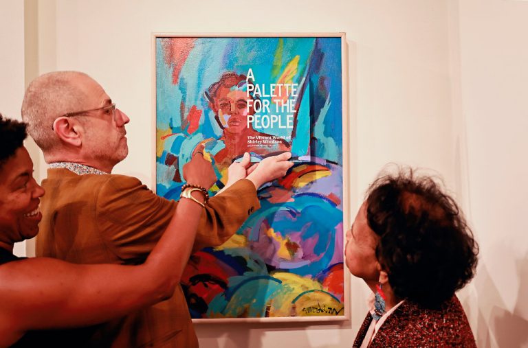 Designer Patrick Barber holds the cover of "A Palette for the People" against Shirley's "Bather with Angel Wing" painting, which is the cover art.