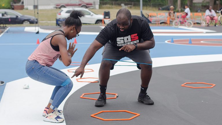 A adult male and young teen are playing a game in a playground