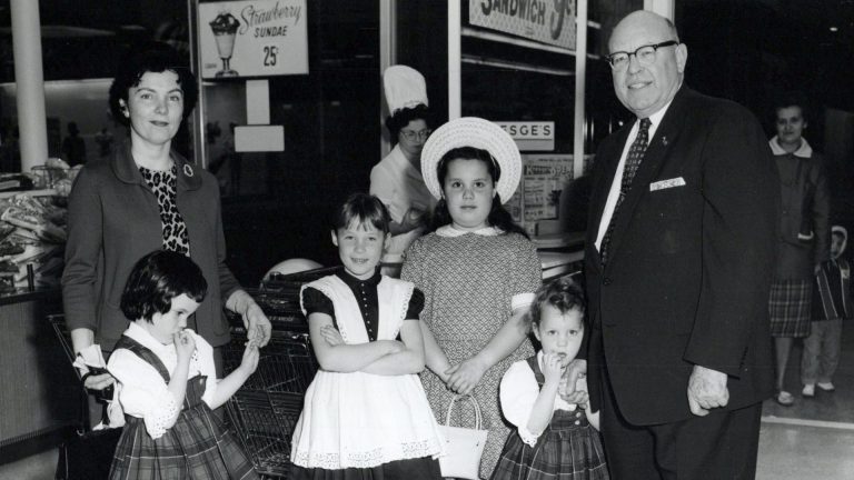 A black-and-white photo circa 1962 of a mother with her four daughters in dresses and the daughters' grandfather in a suit at an S.S. Kresge Co. store.
