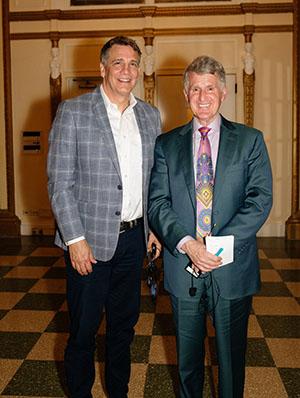 Two men in suits stand together and pose for a photo