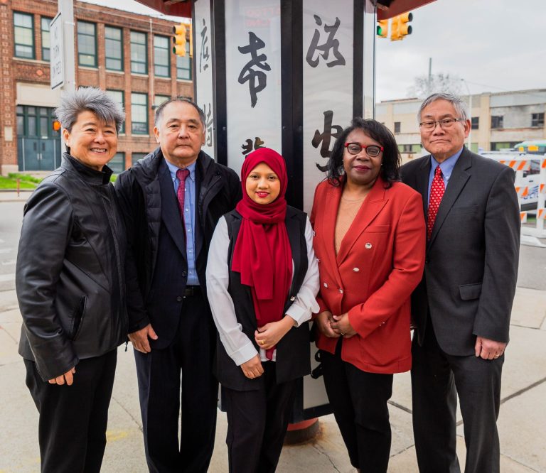 Group of five posed in front of signage designating Detroit's traditional Chinatown