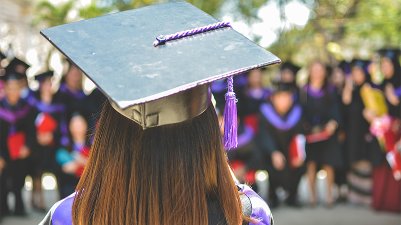 The back of a head of college graduate wearing a cap and gown.