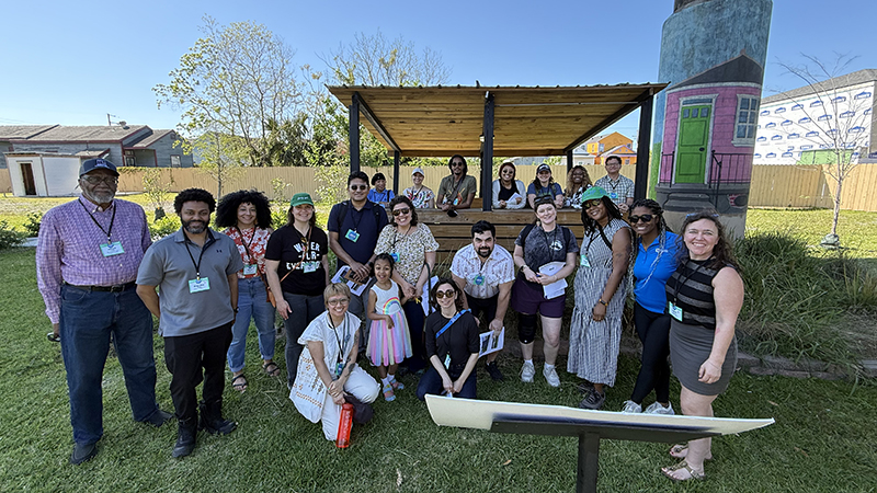 A group of about 20 people (members of Kresge's CREWS initiative) gather in a stormwater park