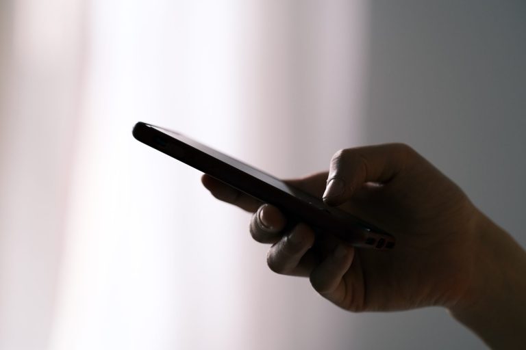 A hand is seen texting on a smartphone.