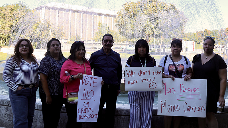 A group of seven people are holding up protest signs, including one that reads Vote No on Central Transport