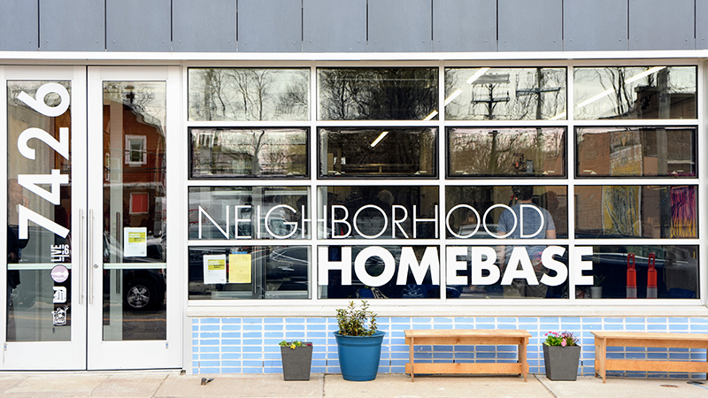 The front of a building with lots of glass window s and a sign: 7426 Neighborhood Homebase