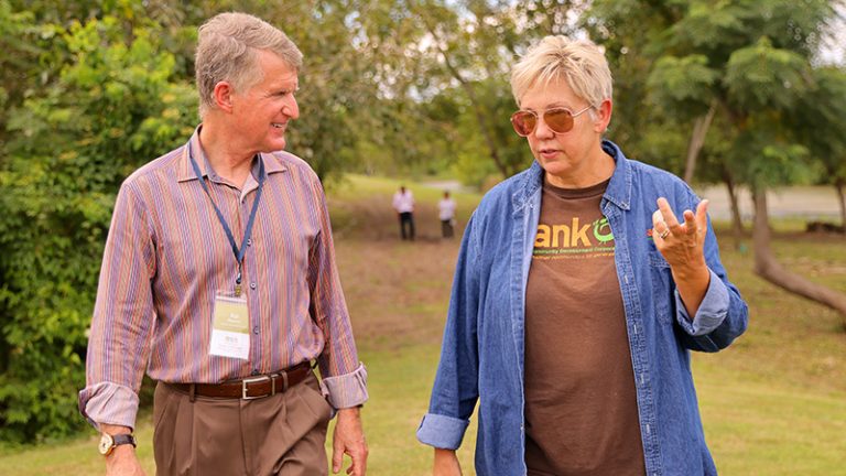 Kresge President Rip Rapson and a grantee representative wearing a Sankofa shirt walk through a wetland park.