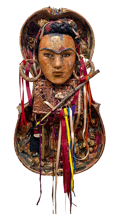 An art piece by Nora Chapa Mendoza entitled "Frida" that stands five feet tall. It includes an image of the artist Frida Kahlo encased in half a violin case.
