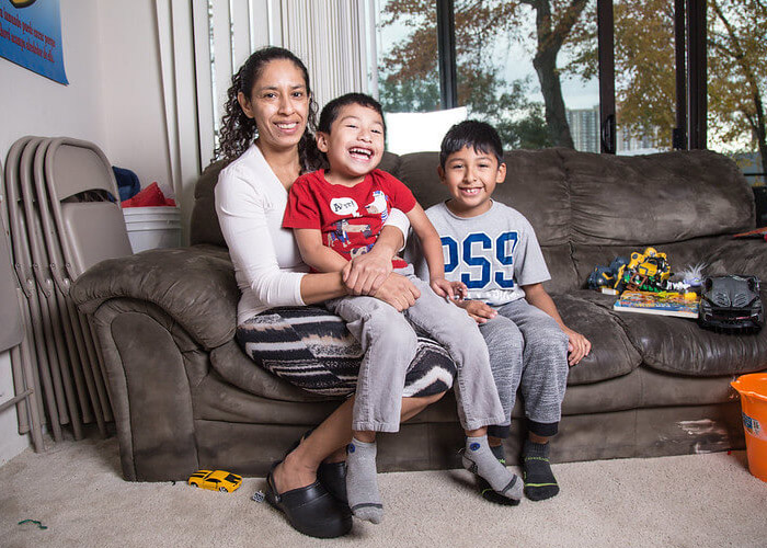 A woman sits on a couch with two children
