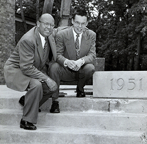 Stanley Kresge and his son Bruce kresge crouch down on steps with a block that has the year 1951 etched on it on the campus of Albion College 