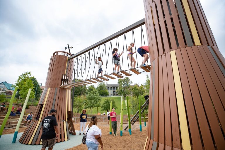 Children are playing on a bridge-like structure in a park. 